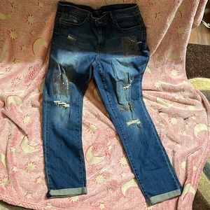Pair of jeweled jeans with some holes in it. Rolled up at the bottom.